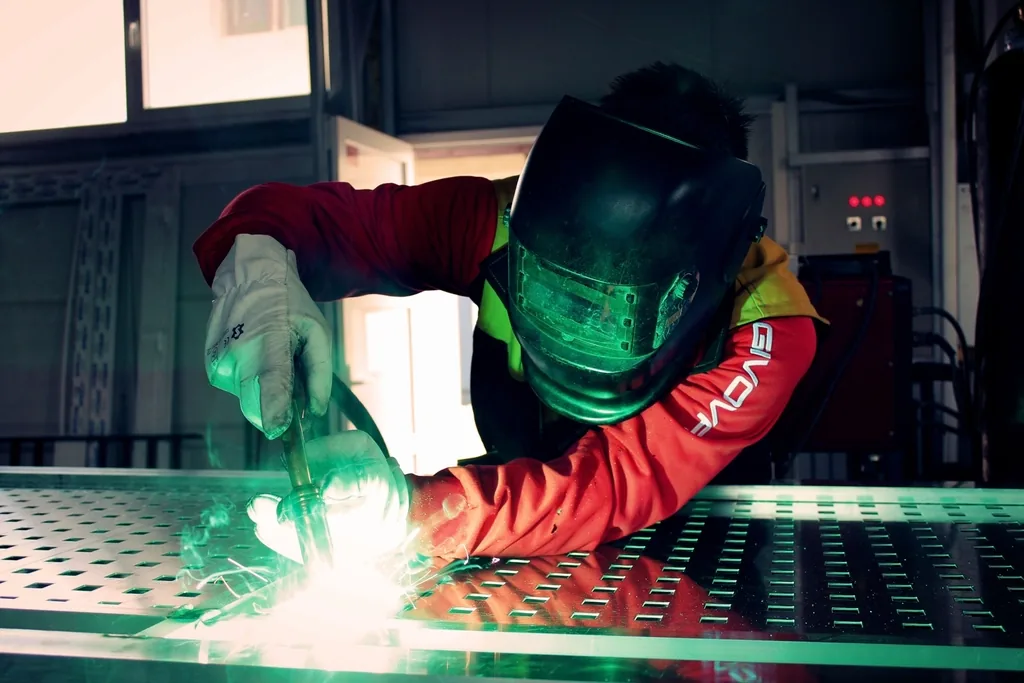 Welder in a helmet and gloves working with sparks flying