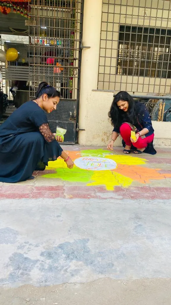 Drawing a Happy Holi rangoli at the entrance